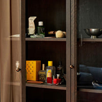 "Dark wood cabinet showcasing vibrant yellow, red, and green products with subtle textures and patterns."