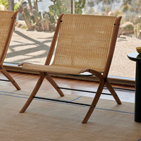 Natural woven rattan chair with a light tan color, featuring a minimalist design and smooth wooden frame.