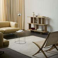 Modern living room featuring soft beige sofa, light wood shelving, and neutral curtains with a minimalistic design.