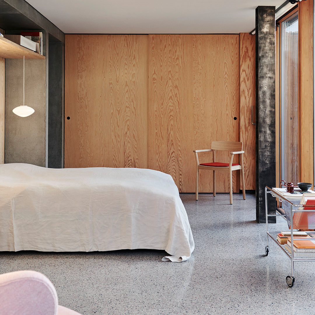 Light cream bedding on a soft gray floor, complemented by warm wooden accents and a modern minimalist aesthetic.