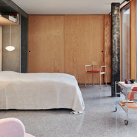 Light cream bedding on a soft gray floor, complemented by warm wooden accents and a modern minimalist aesthetic.