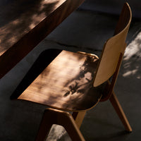 Modern wooden chair featuring a warm brown finish with smooth, contrasting light and shadow patterns.