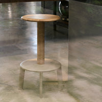 Light wood stool with a smooth, natural finish; circular top and base featuring subtle textures and warm tones.