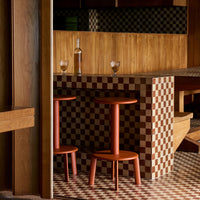 "Red and cream checkered pattern with earthy wood tones in modern café setting."