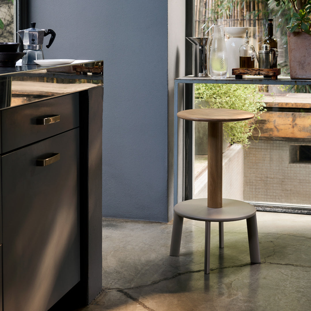 Modern two-tone round stool with natural wood top and gray legs, set against a stylish kitchen backdrop.