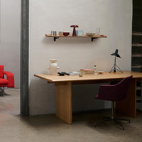 Modern wooden desk with purple chair, featuring gray walls and minimalist decor in earthy tones and subtle patterns.