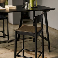 Black wooden table with dark blue and brown patterned chairs, accentuated by green and glass accessories.