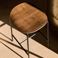 Round wooden stool with a warm walnut finish and sleek black metal legs, showcasing natural wood grain patterns.