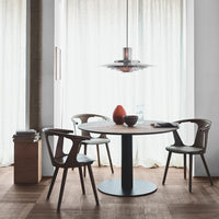 Modern round wooden dining table with brown chairs, featuring a minimalist black base and soft neutral tones in the background.