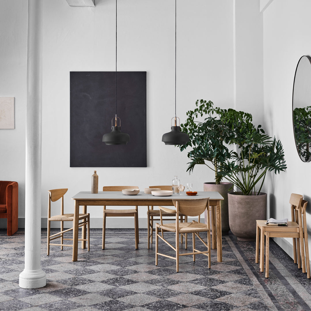 "Modern dining room featuring gray patterned tiles, wooden furniture, and green foliage against a white and dark backdrop."