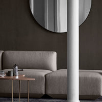 "Modern gray fabric sofa with clean lines, complemented by a round mirror and a neutral wall backdrop."