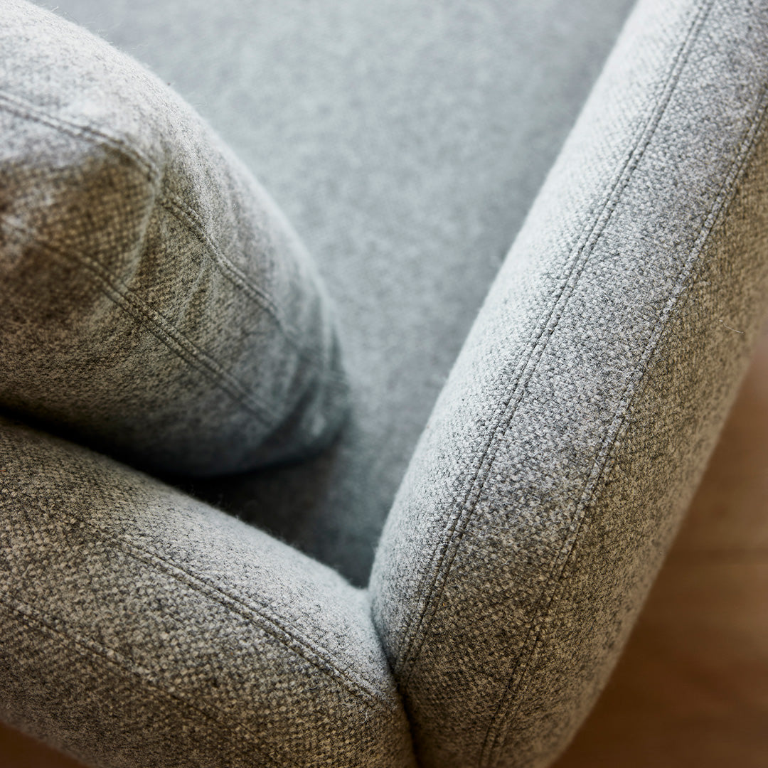 Gray textured upholstery with subtle herringbone pattern on a modern armchair. Soft and inviting design.
