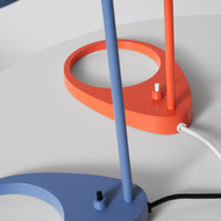 "Colorful lamp base in blue and orange with geometric patterns on a minimalist white surface."