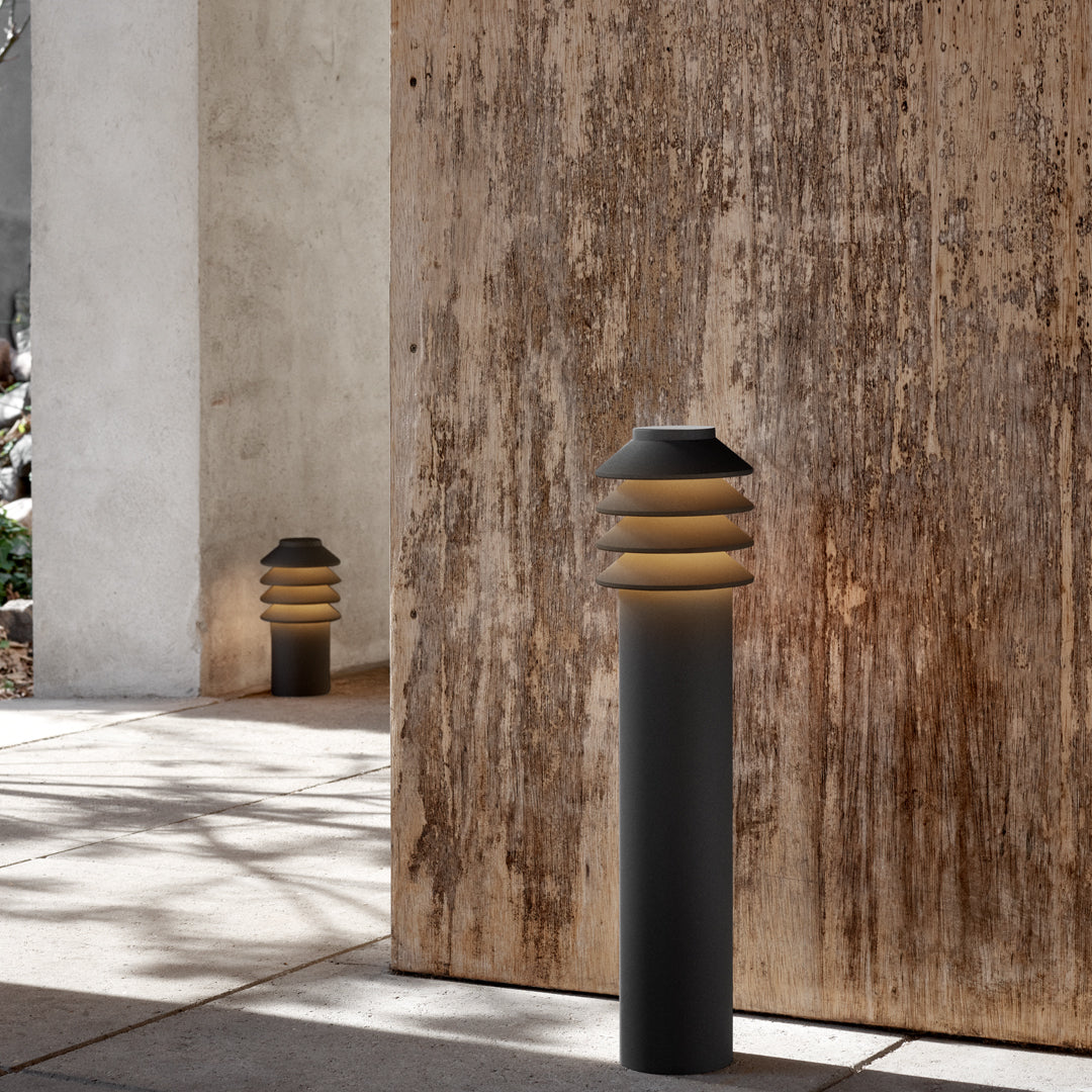 Modern outdoor light with a sleek black finish and unique layered gold top pattern, enhancing contemporary spaces.
