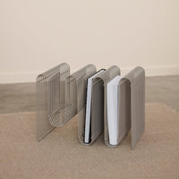 Metal magazine holder in sleek silver with alternating patterns of black and white magazines. Minimalist design.