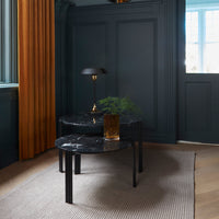Elegant black marble coffee table with subtle white veining, complemented by dark wood legs. Modern, stylish design.