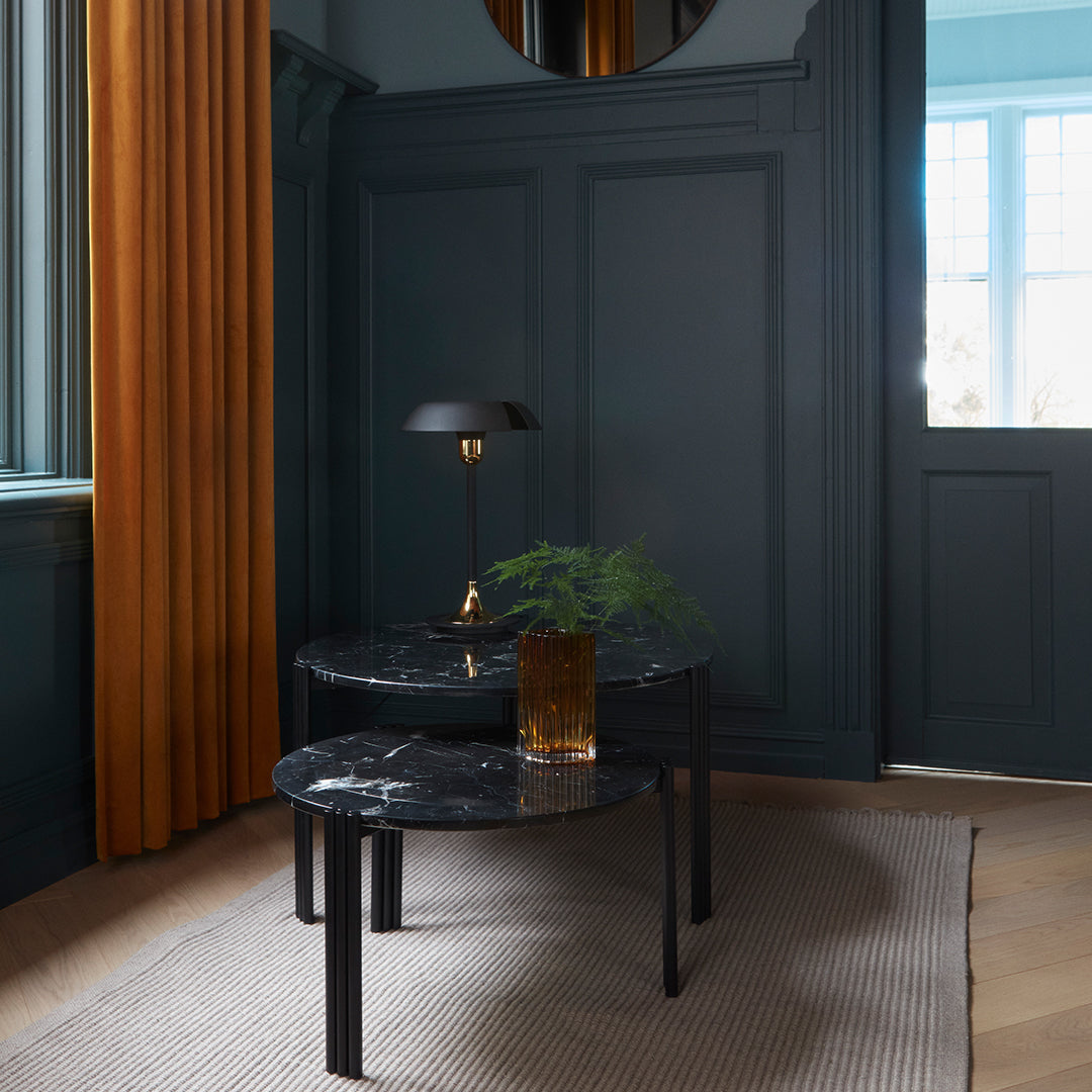 Stylish black marble tables with glossy surfaces, paired with warm gold and deep blue elements in a modern interior.