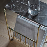 Black marble top with white veining, complemented by golden metal frame and a gray fabric accent.