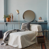 Cozy beige chair cover with a stylish gray throw and patterned pillow, against a soft blue wall backdrop.