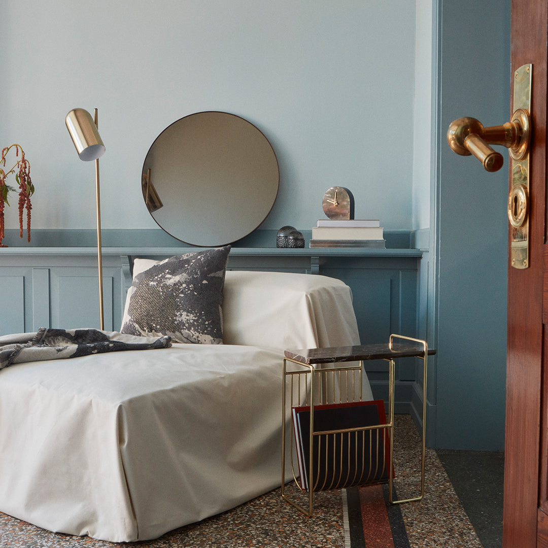 Modern room with light blue walls, neutral slipcover, gray and black patterned cushion, and gold accents.