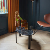 Black marble side table with sleek black legs, complemented by warm amber glass vases and a rich blue wall backdrop.