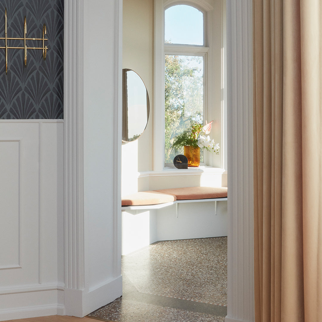 Soft beige curtains, intricate textured wall in dark gray, and warm wooden accents create a cozy and inviting space.