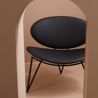 Black oval chair with sleek lines, set against a soft beige background, showcasing modern minimalist design.