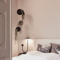 "Soft beige walls with subtle leafy green foliage and gray decorative pillows on a white bed."