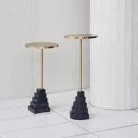 Gold and black geometric accent tables with sleek round tops and stepped bases, perfect for modern decor.