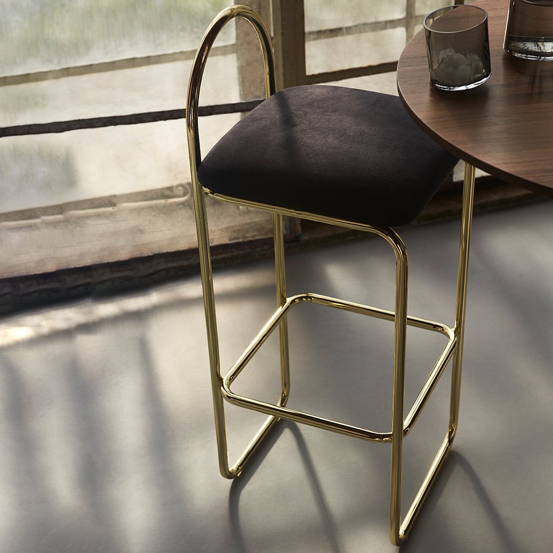 Black upholstered bar stool with a sleek gold metal frame, featuring clean lines and modern design elements.