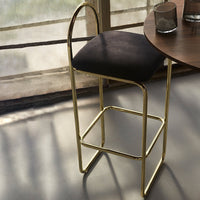 Black upholstered bar stool with a sleek gold metal frame, featuring clean lines and modern design elements.