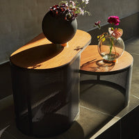 "Stylish black mesh and wood coffee table with natural finish, featuring smooth curves and geometric patterns."