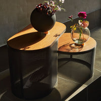 Modern two-tone coffee table with an oak top and black mesh base, featuring elegant floral arrangements.
