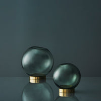 "Set of two rounded glass vases in smoky gray with sleek gold bases, showcasing minimalistic elegance for modern decor."