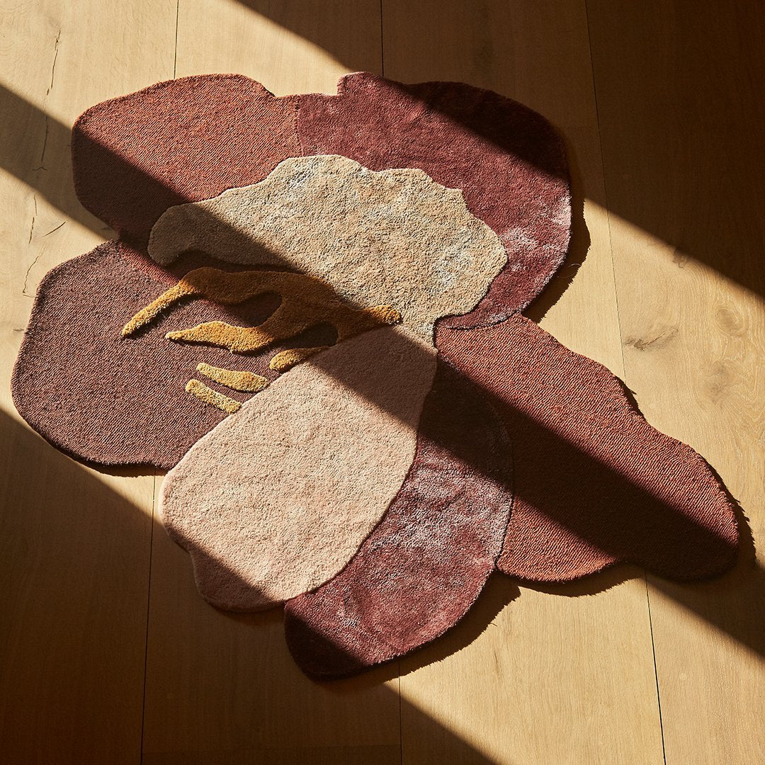 Multicolored floral rug in warm shades of burgundy, tan, and neutral tones with abstract design patterns.