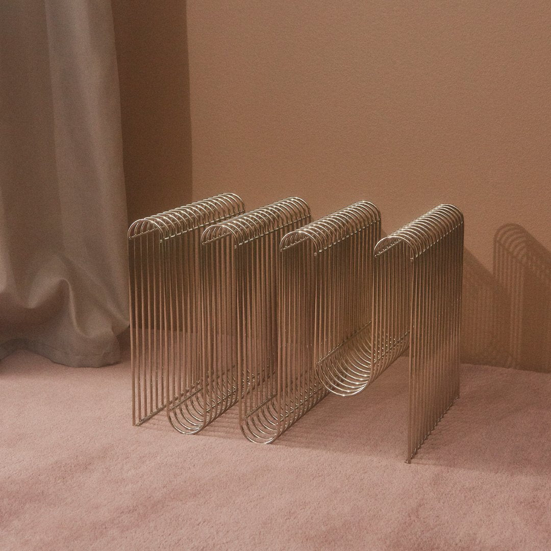 Metal bookend set with sleek metallic lines, showcasing a minimalist design against a soft pink background.