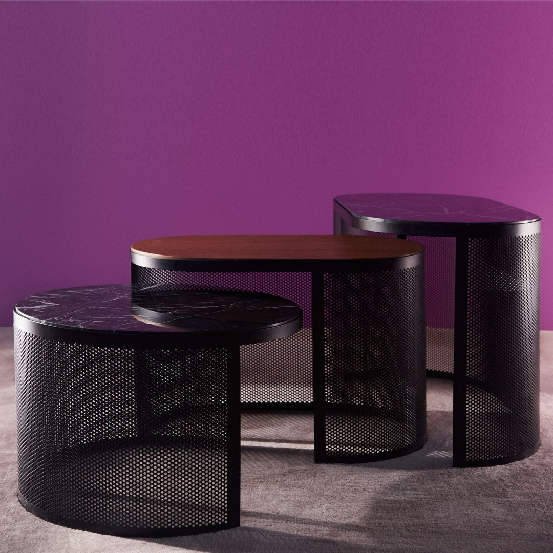 Three modern tables featuring black metal mesh and contrasting wood surfaces against a vibrant purple backdrop.