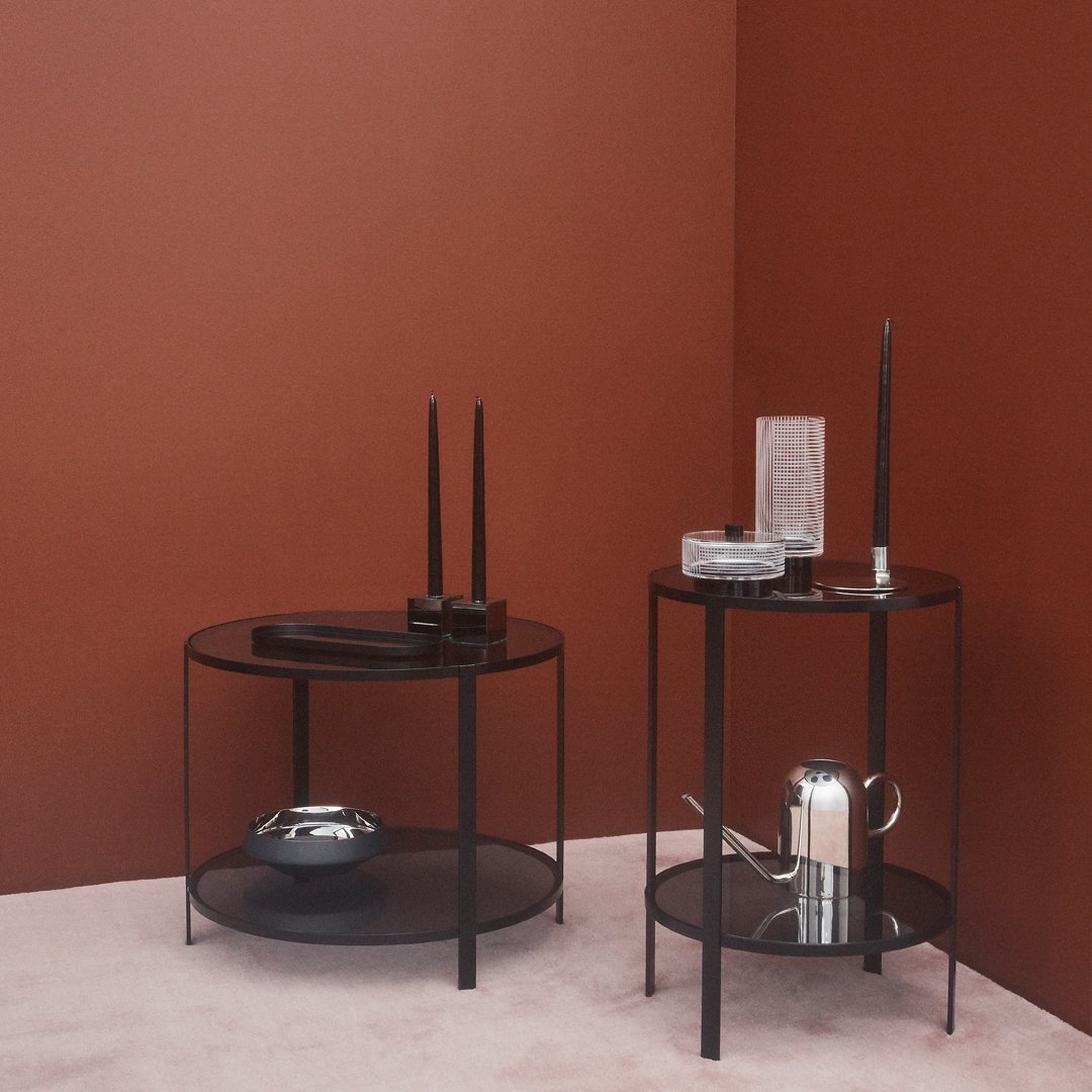 "Two modern black side tables against a rich brown wall, showcasing sleek lines and minimalist design."