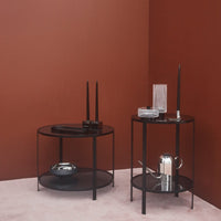 "Two modern black side tables against a rich brown wall, showcasing sleek lines and minimalist design."