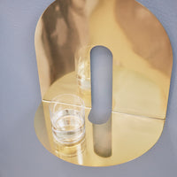Gold metallic wall shelf with a sleek curved design, featuring a reflective finish and minimalist aesthetic.