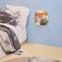Cozy bedroom setting with gray and taupe textures, gold accent shelf, and soft blue wall. Patterns add warmth and style.