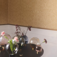 Colorful glass vases in shades of pink, green, and amber, with elegant floral arrangements, set against a textured gold wall.
