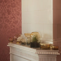 Gold and amber decorative bowls against a soft pink wallpaper with subtle floral patterns. Elegant home decor accent.