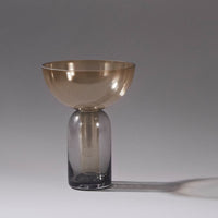 Smoked glass vase with a sleek, rounded gray bottom and a shimmering gold bowl on top. Perfect for modern decor.