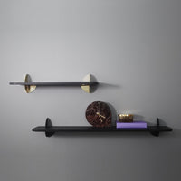 Stylish black shelves with gold brackets, featuring a rich marble clock and purple accents against a gray wall.