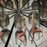"Gray textured glasses with pink and orange decorative elements reflecting in a mirrored surface."