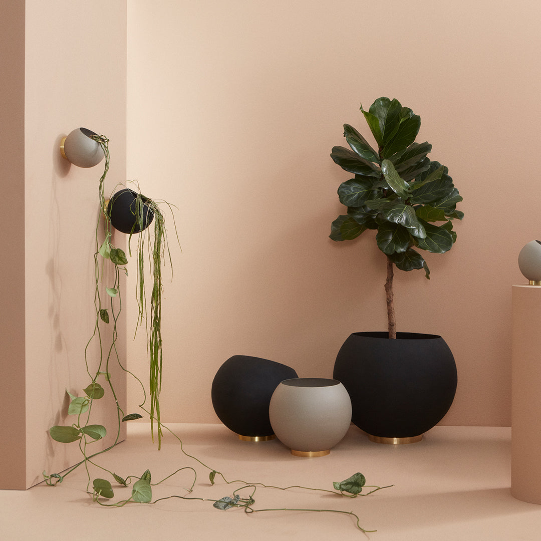 Modern planters in black, gray, and soft pastel tones with minimalistic shapes against a warm, neutral backdrop.