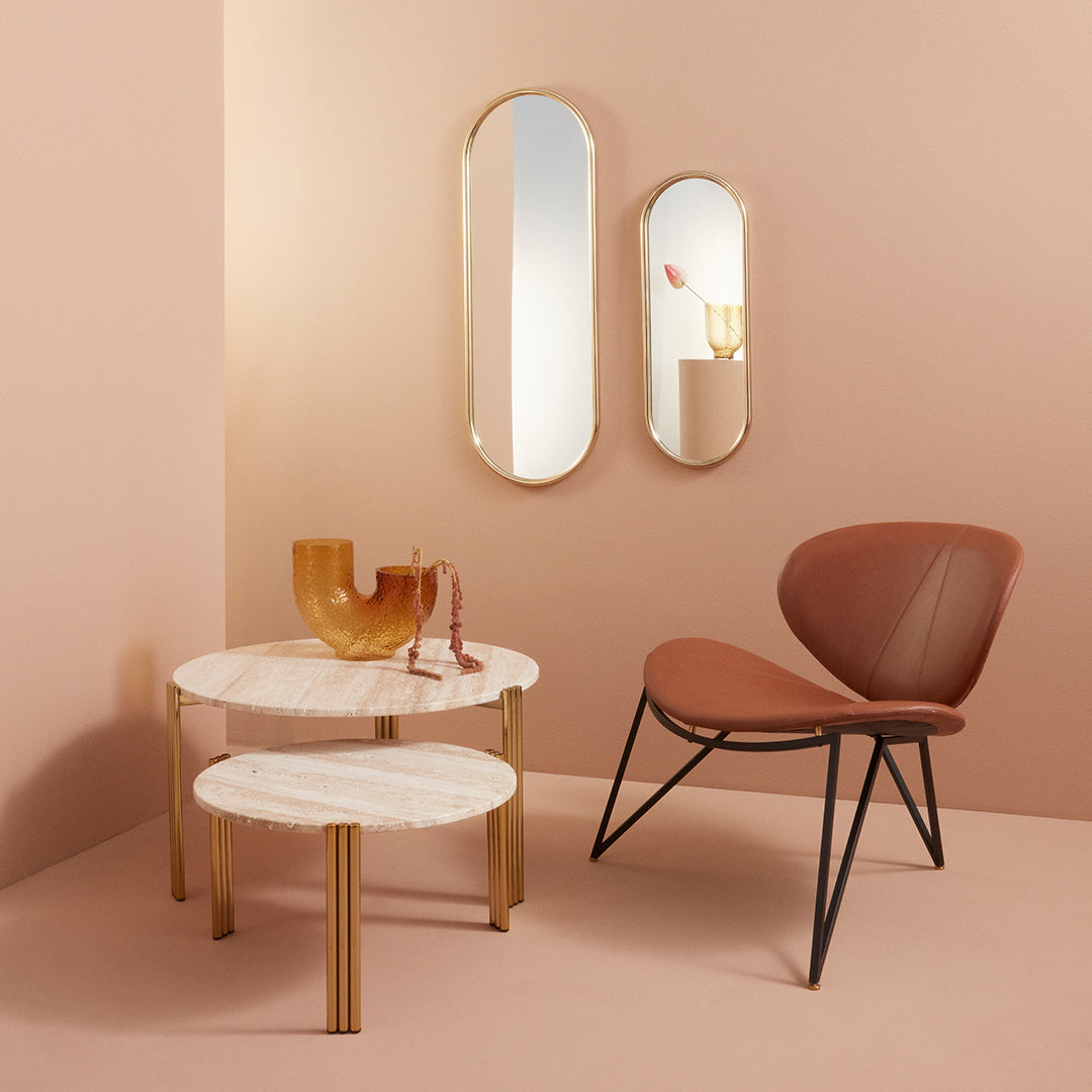 Elegant marble tables with gold legs, complemented by a tan chair against a soft pink backdrop. Modern, stylish design.
