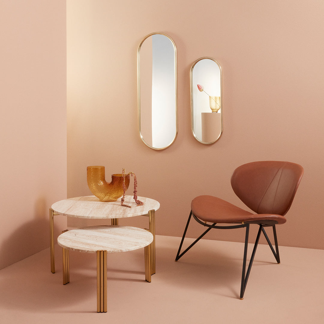 Elegant brown chair, round marble tables, and gold accents against a soft pink backdrop, creating a modern, stylish vibe.