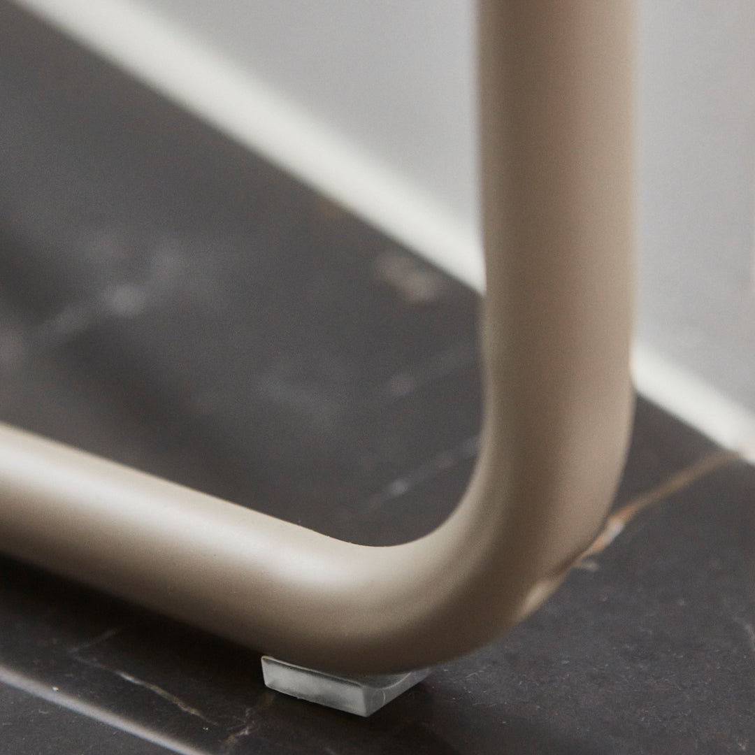 Beige furniture leg against a dark marble surface, showcasing subtle texture and smooth curves.
